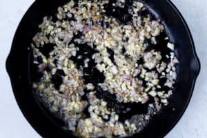 Garlic and shallot cooking in a cast iron skillet