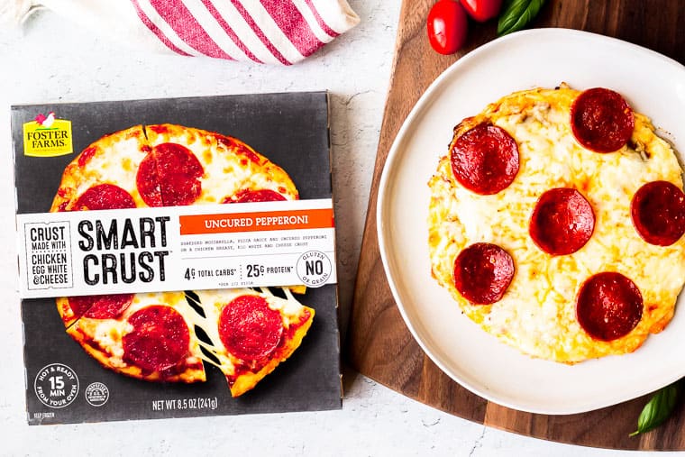 A Poster Farms Smart Crust Uncured Pepperoni Pizza on a plate next to the packaging