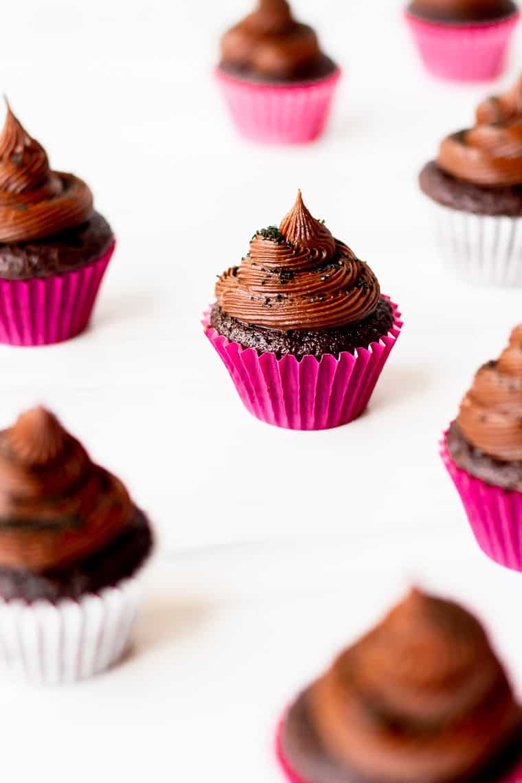 Mini chocolate cupcakes with chocolate buttercream frosting on a white background