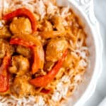 Close up of a bowl of coconut curry chicken and rice with text overlay.