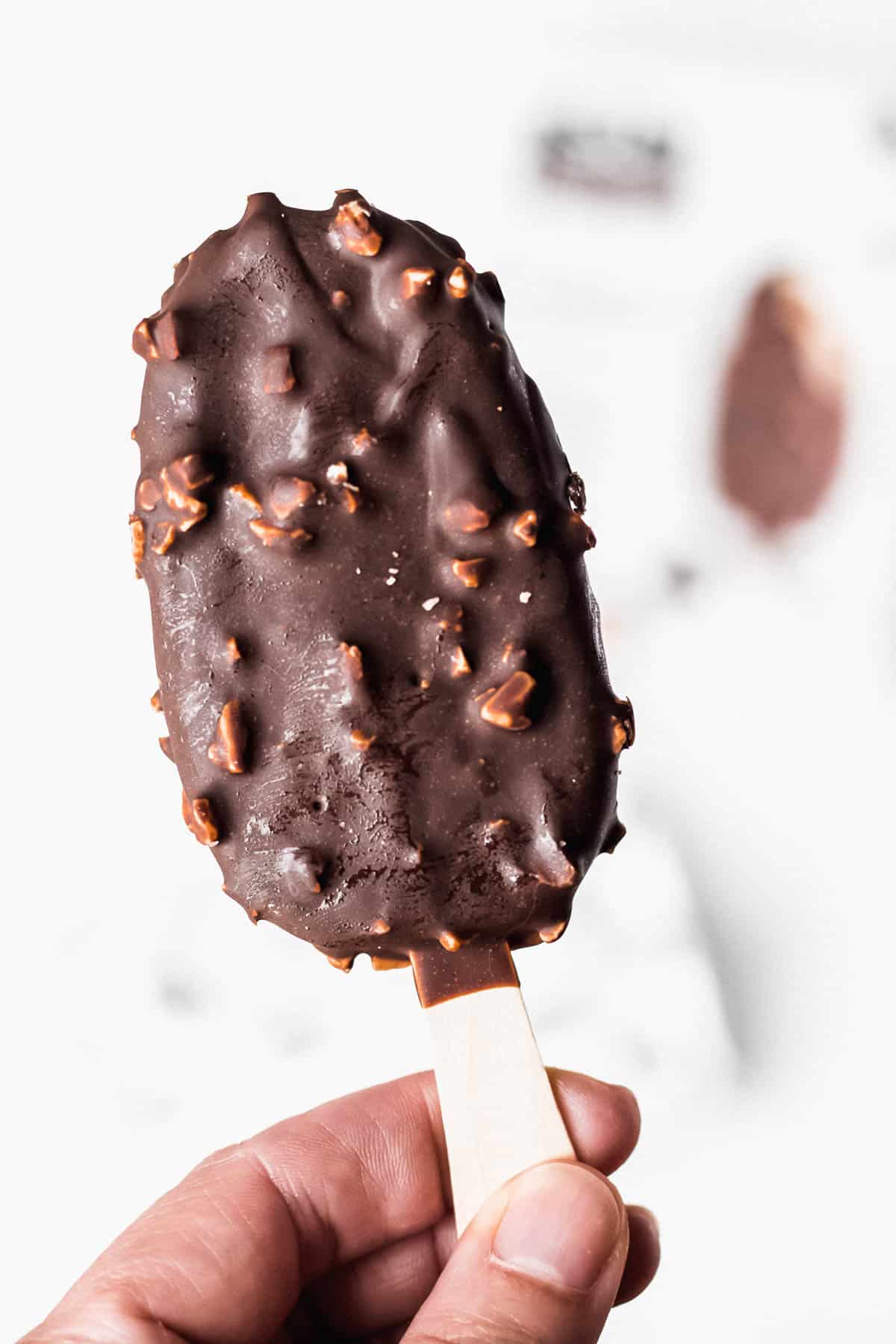 An ice cream bar on a stick being held up in 