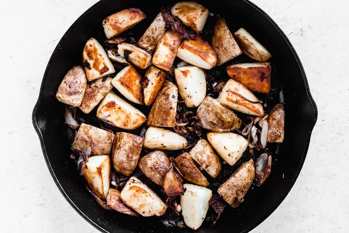 Roasted potatoes and shallots in a cast iron skillet