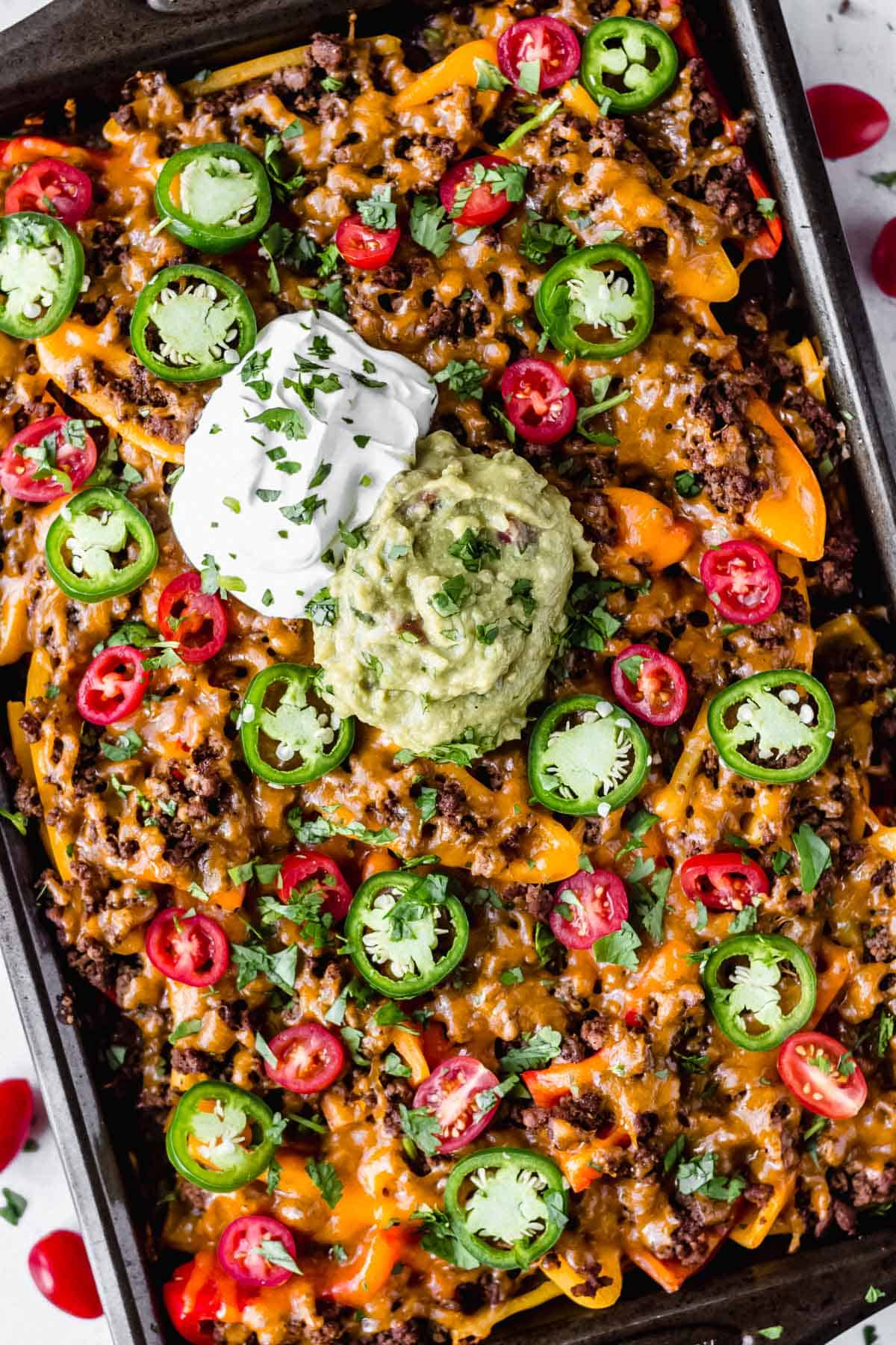Overhead of a tray of loaded bell pepper nachos topped with sour cream and guacamole