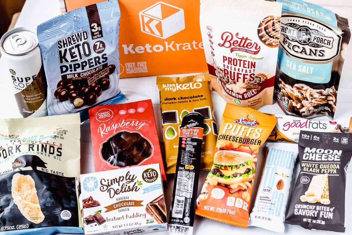 All of the snacks that come in the February 2021 keto krate laid out around the box on a white background