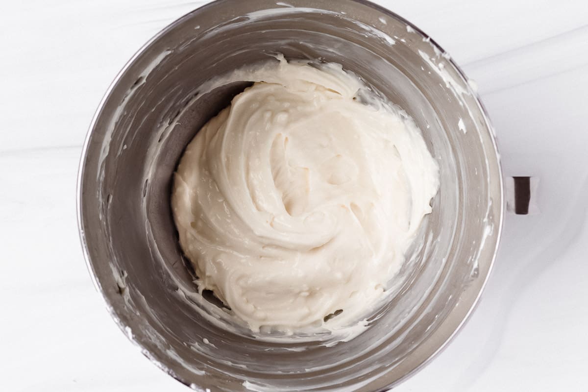 Vanilla cream cheese frosting in a silver mixing bowl over a white background