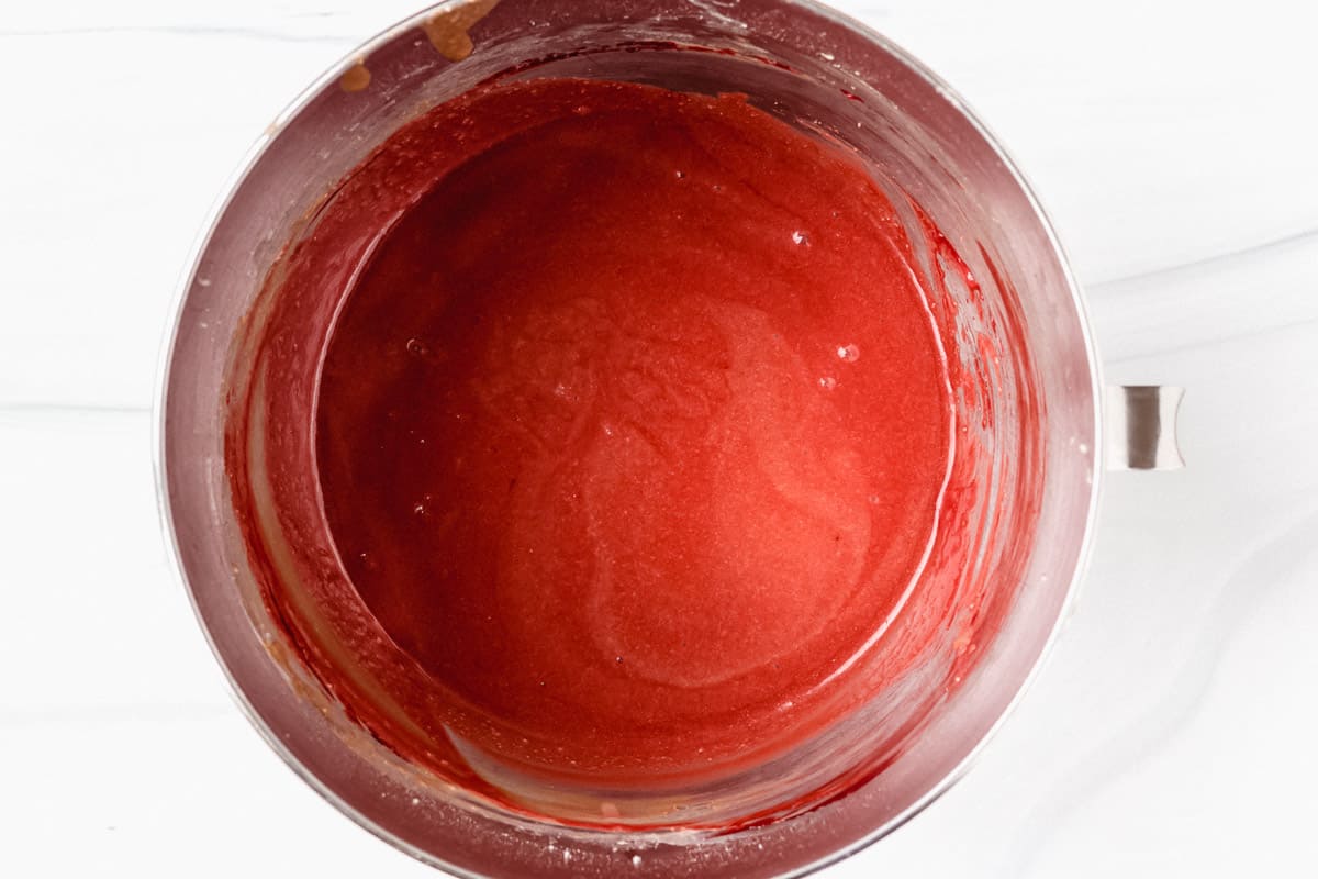 Red velvet cake batter in a silver mixing bowl over a white background