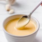 roasted garlic hollandaise sauce in a bowl with a spoon with text overlay
