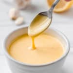 roasted garlic hollandaise sauce in a bowl with a spoon with text overlay