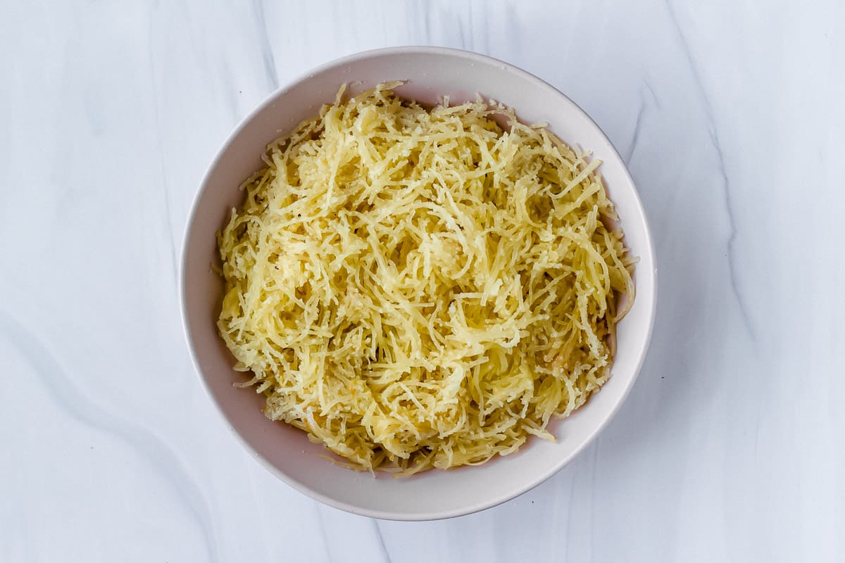 A light pink bowl filled with spaghetti squash and cheese