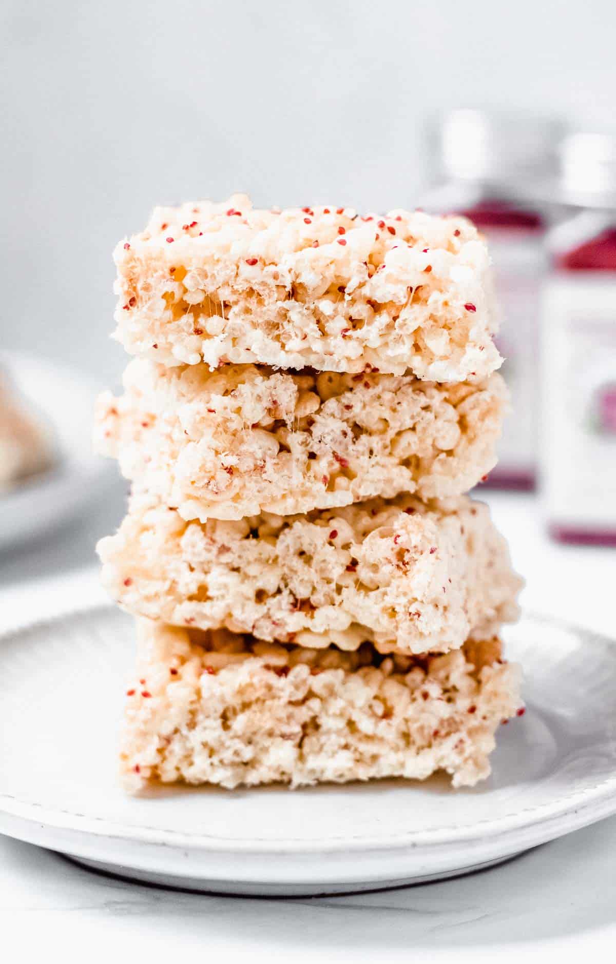 Stack of 4 crispy cereal treats with cranberry seeds in a white plate