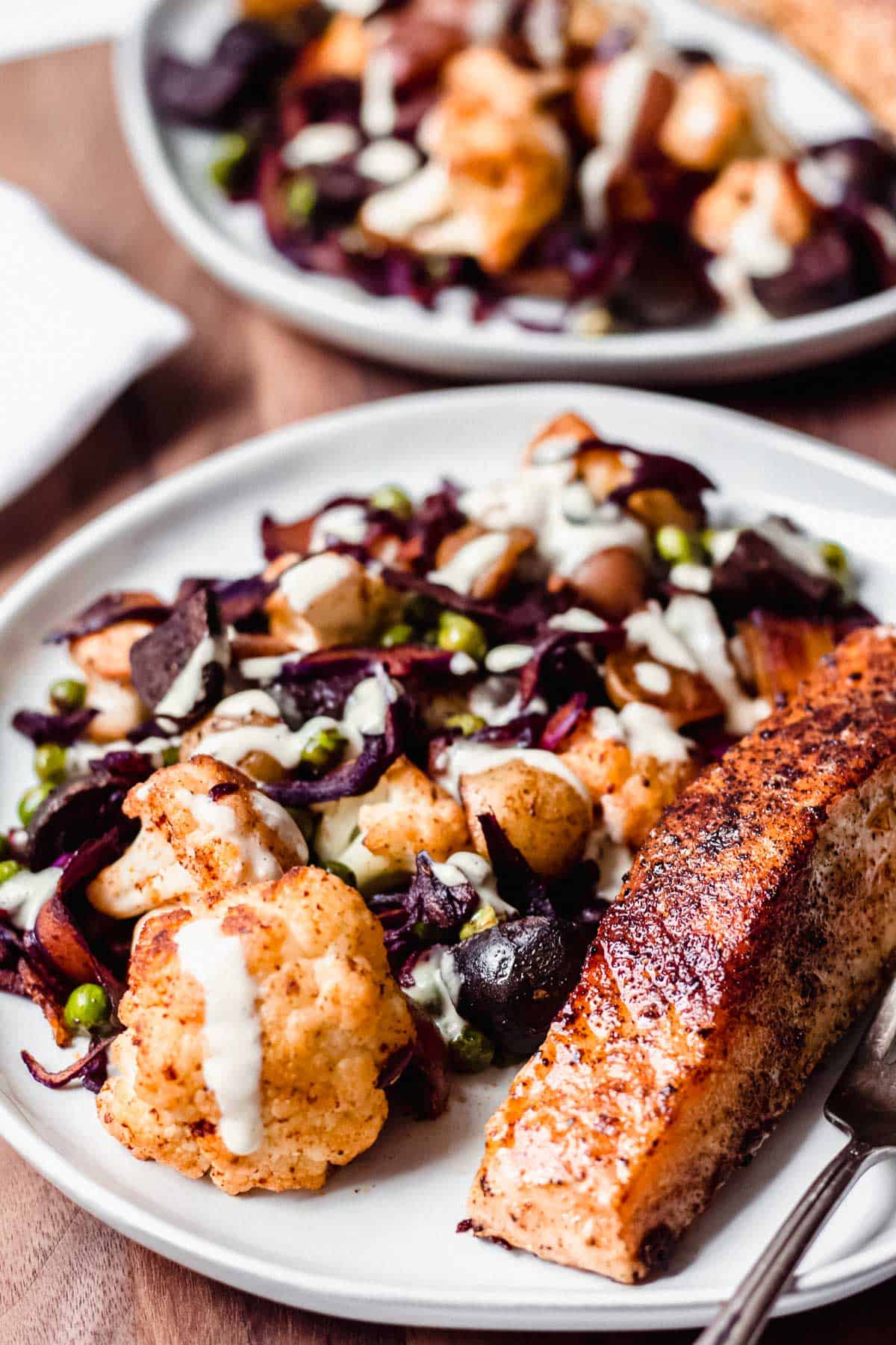 Pan-Seared Salmon Fillets with Colorful Vegetable Hash on white plates on a wood board