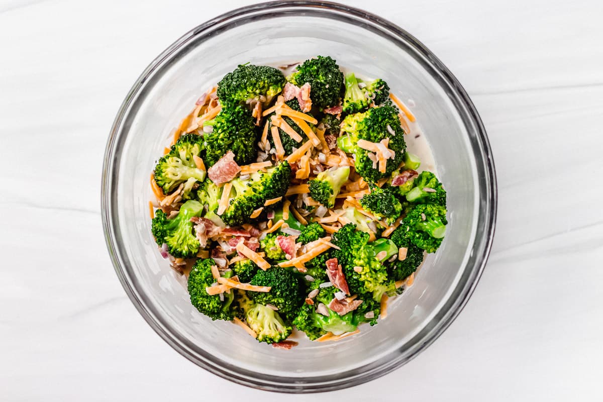 Broccoli salad in a glass bowl on a white backdrop