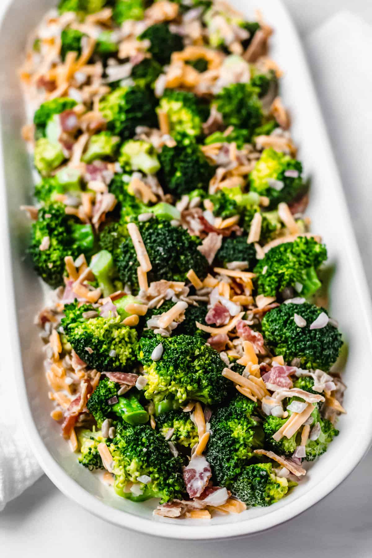 white oval serving tray filled with keto broccoli salad on a white backdrop