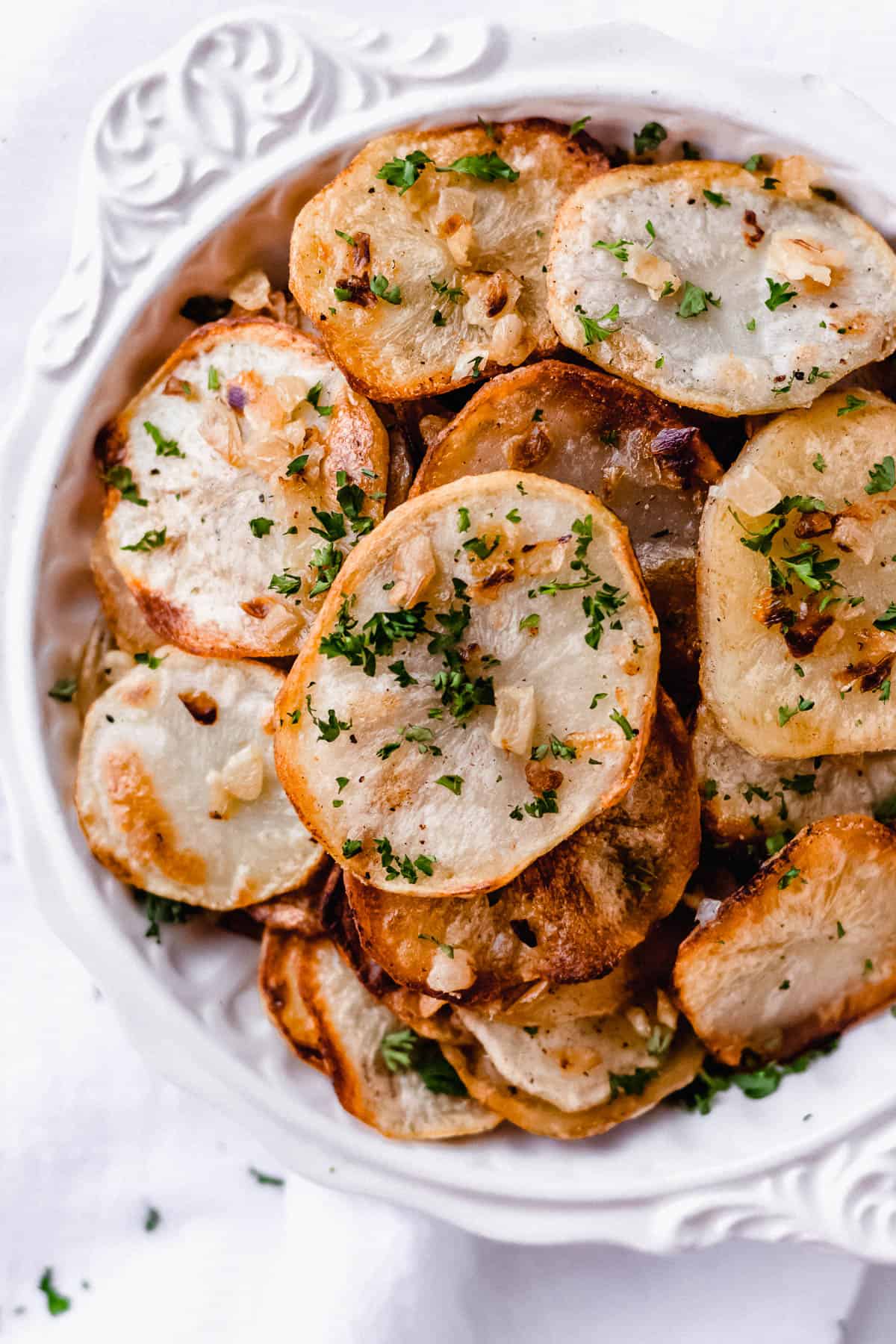 Close up of lyonnaise potatoes in a white bowl