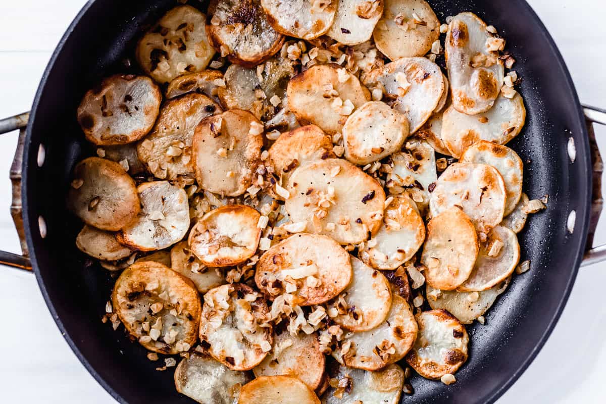 Potato slices and onions in a black skillet