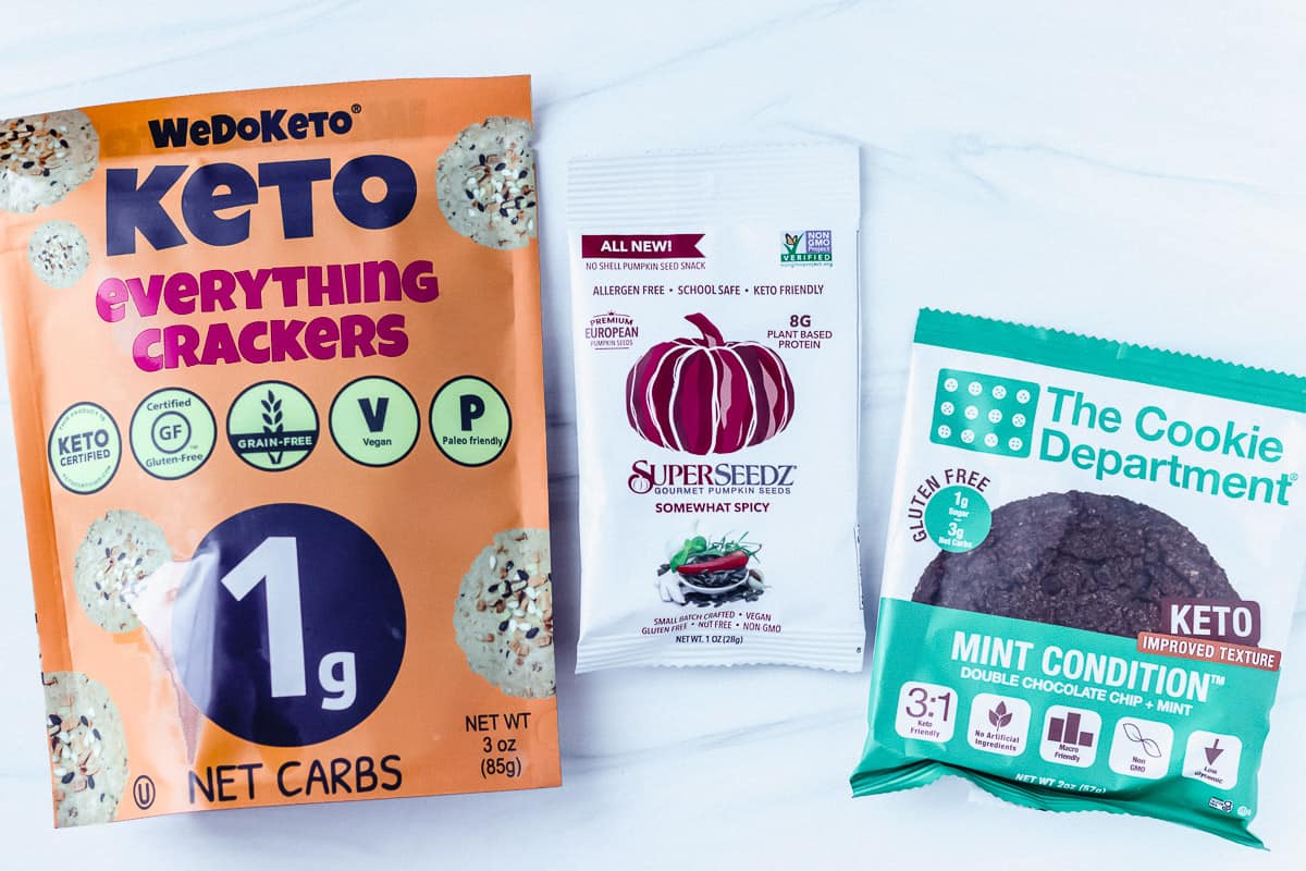 Keto crackers package, sunflower seeds package and keto cookie package on a white background