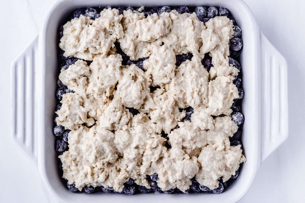 Prepared blueberry cobbler in a white baking dish prior to baking