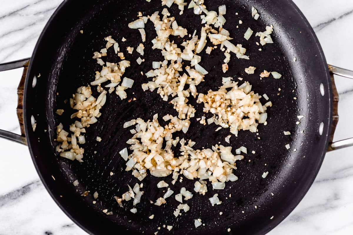 Garlic and onion cooking in a black skillet