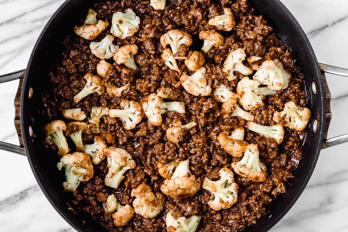 Barbecue ground beef and cauliflower florets in a black skillet