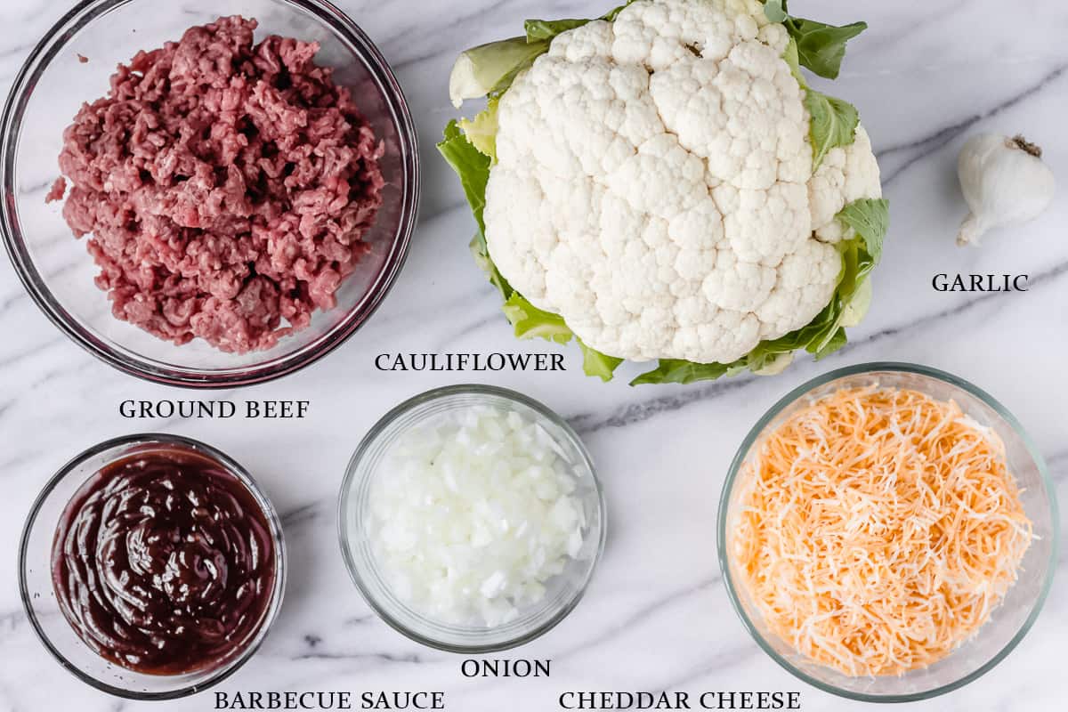 Ingredients for a barbecue ground beef and cauliflower skillet on a marble table with labels