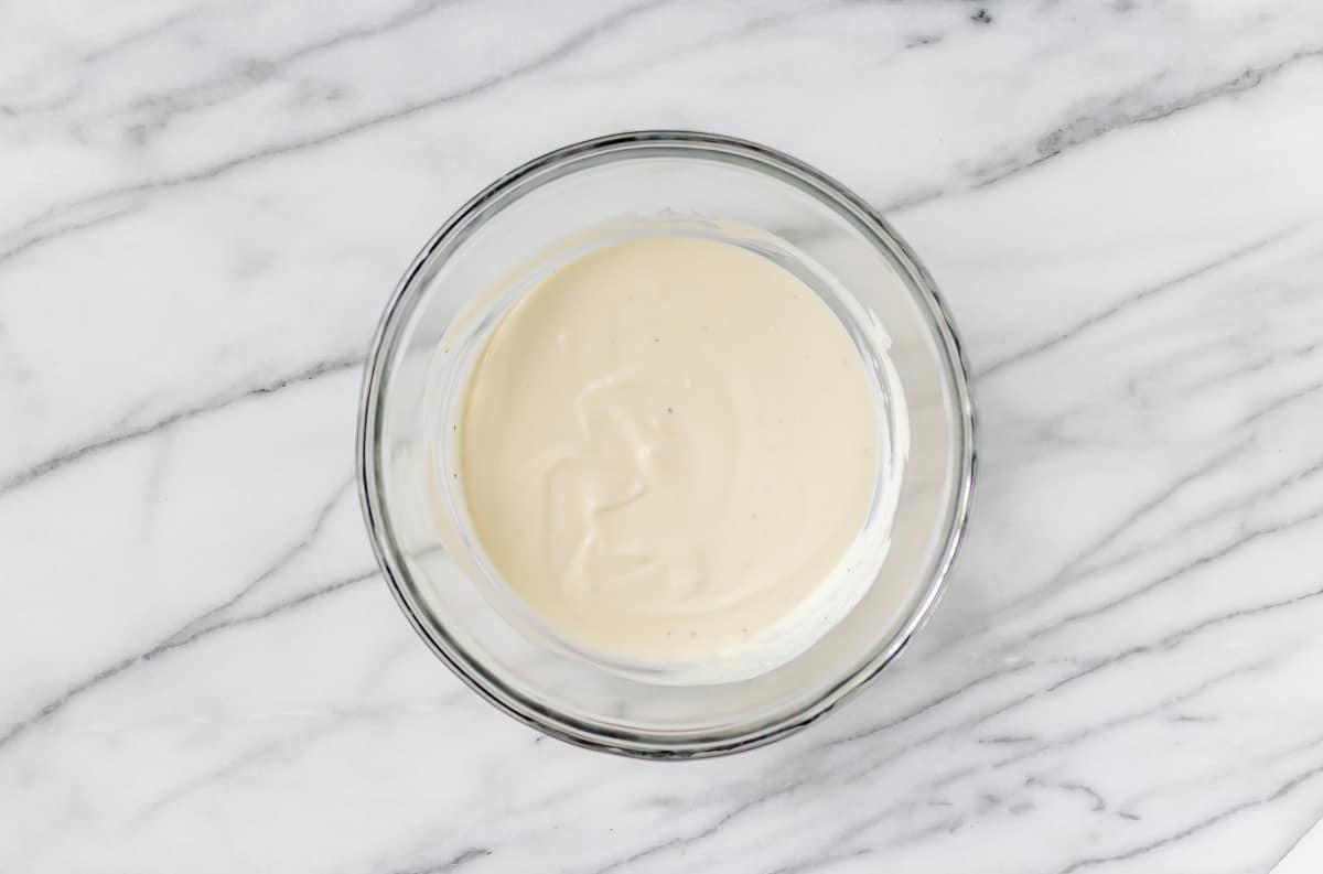 Mayonnaise dressing in a glass bowl on a marble background