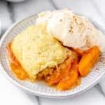 Close up of apricot cobbler and ice cream on a white plate