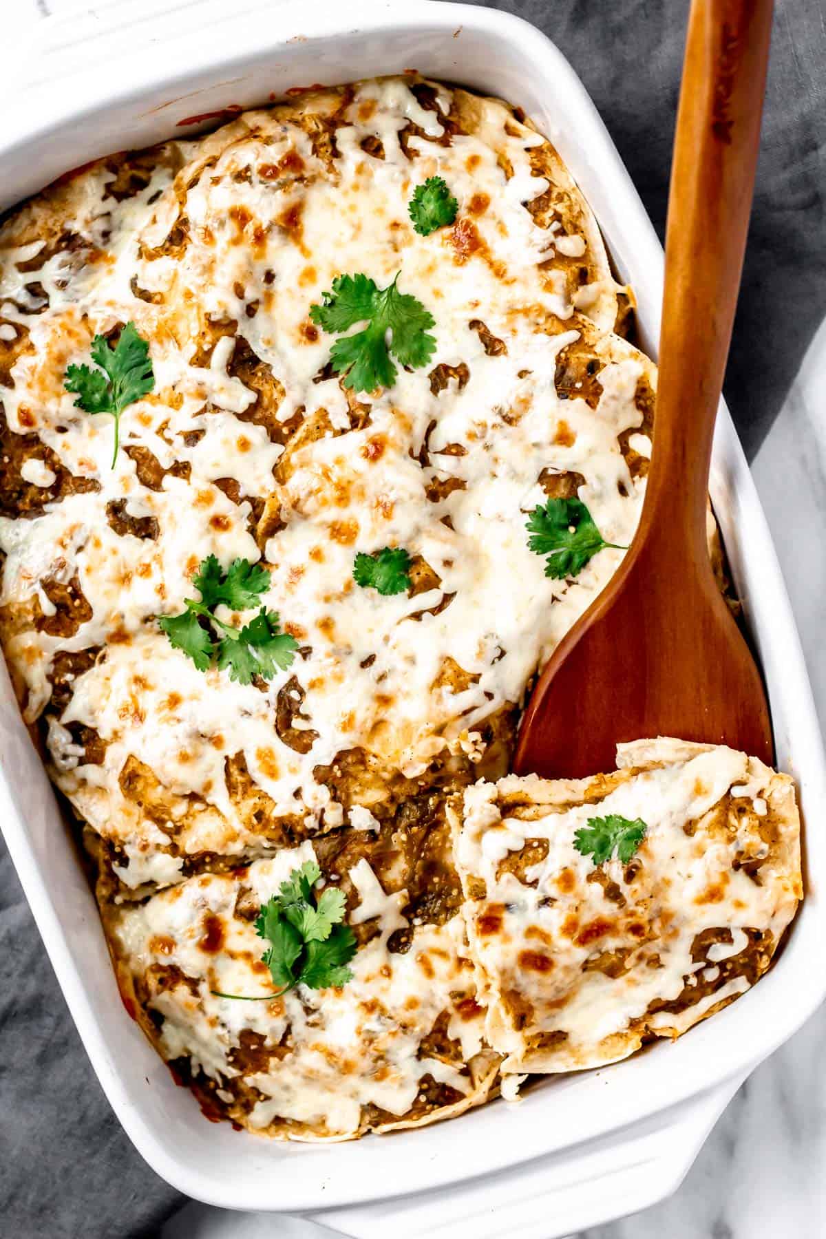 Overhead of chicken enchilada casserole with a wood server under a serving