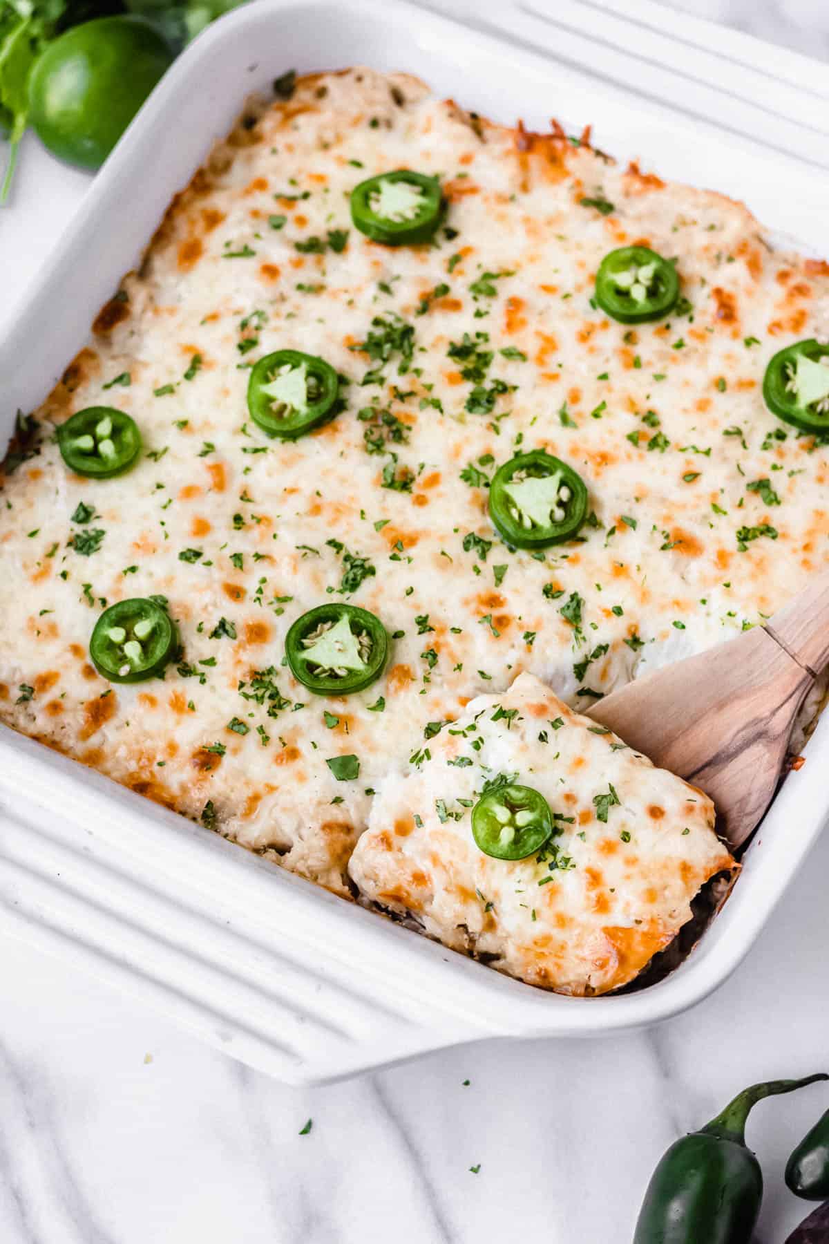 Salsa Verde Chicken Casserole with a wood spoon lifting up a portion