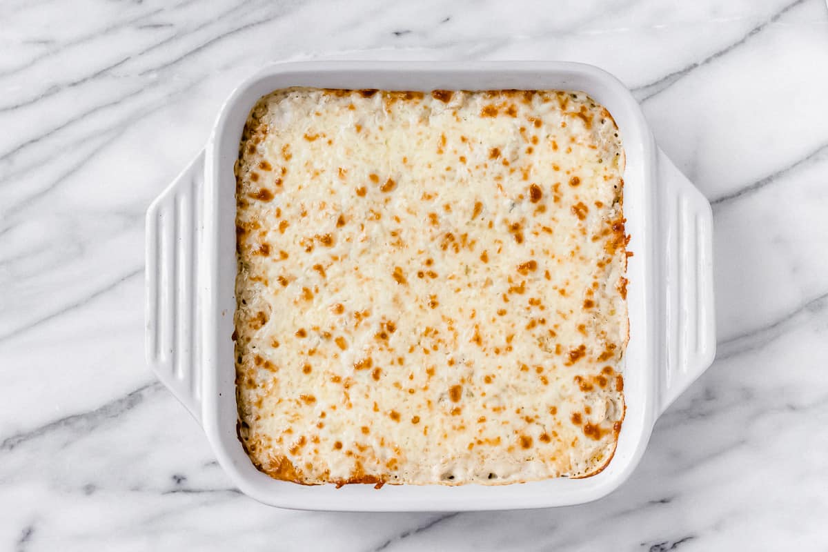 Browned, melted cheese topped casserole in a white, square baking dish
