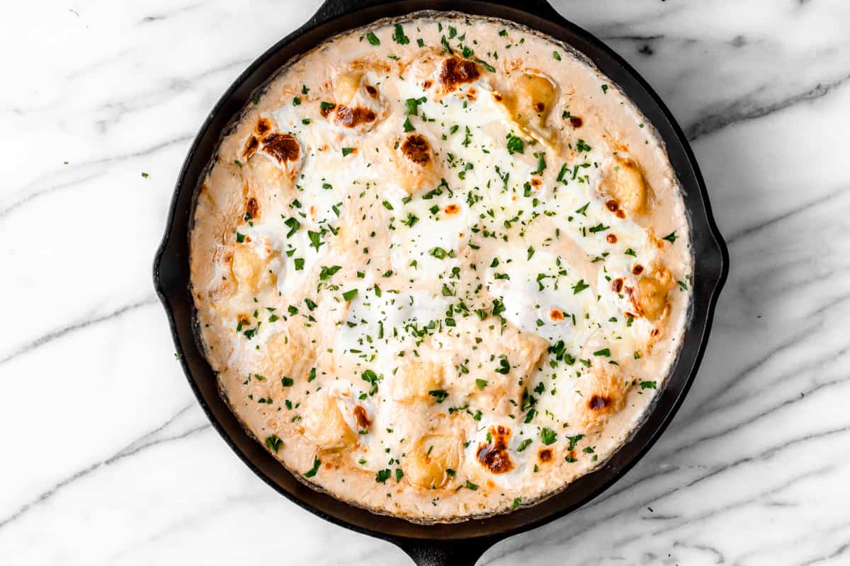 Baked Ravioli Casserole in a cast iron skillet over a marble background