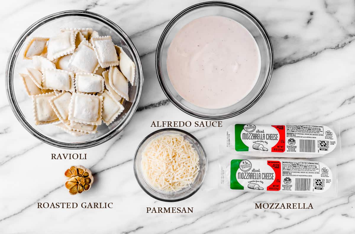 Ingredients needed to make ravioli alfredo on a white background with labels