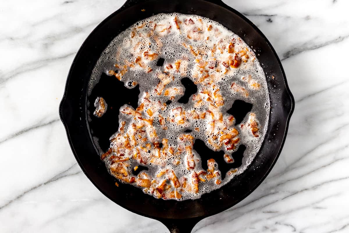 diced bacon cooking in a cast iron skillet