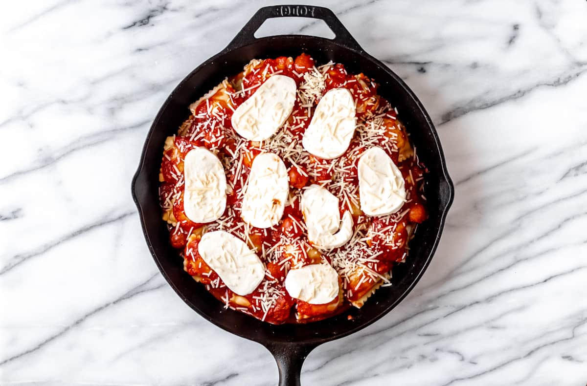 Ravioli casserole prior to baking in a cast iron skillet