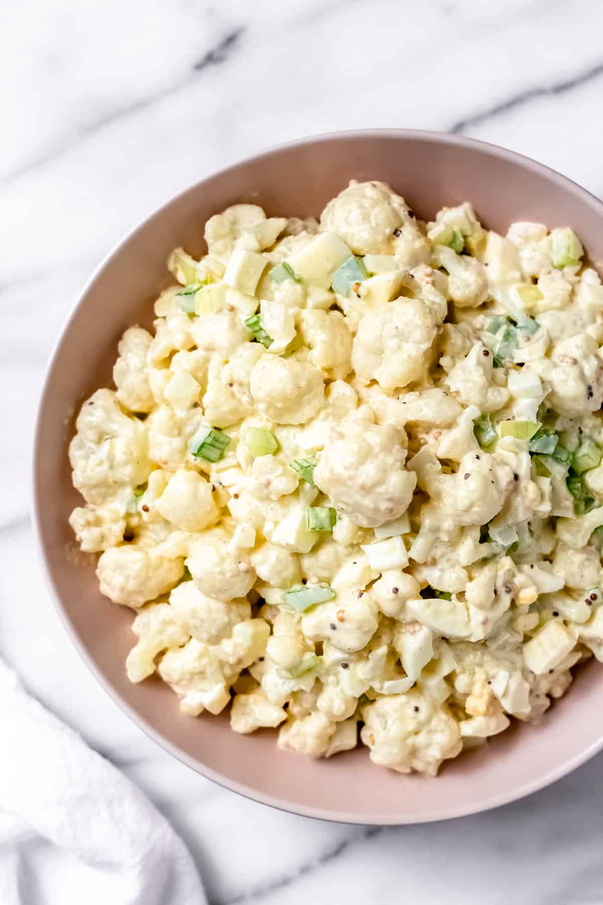 Keto potato salad in a pink bowl over a marble background