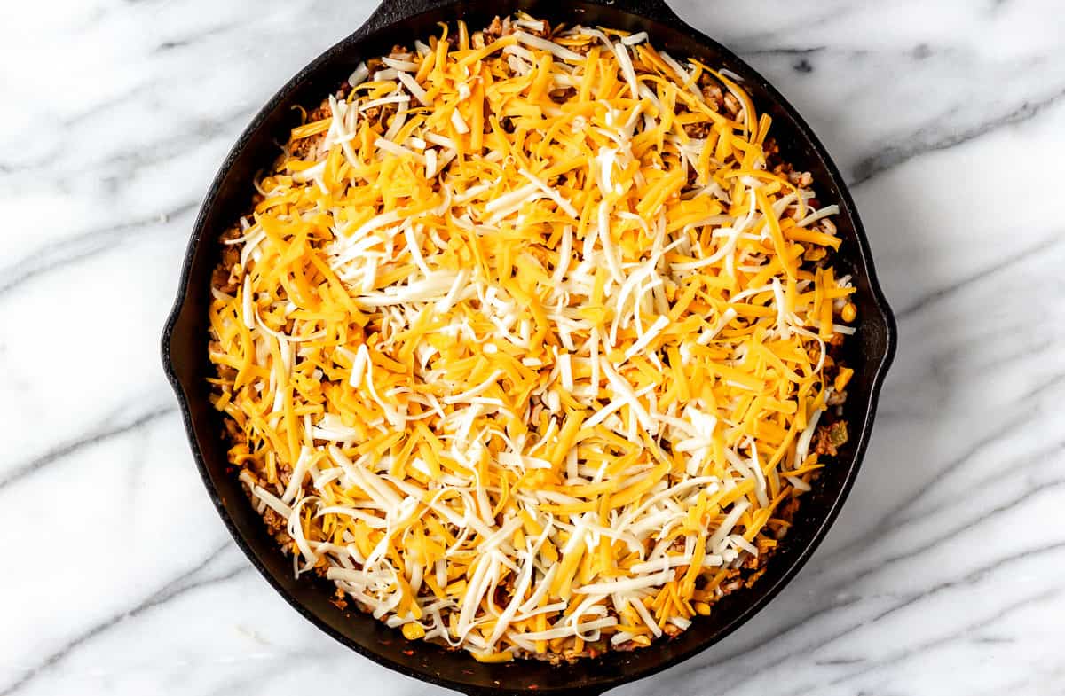 Cast iron skillet meal topped with shredded cheese