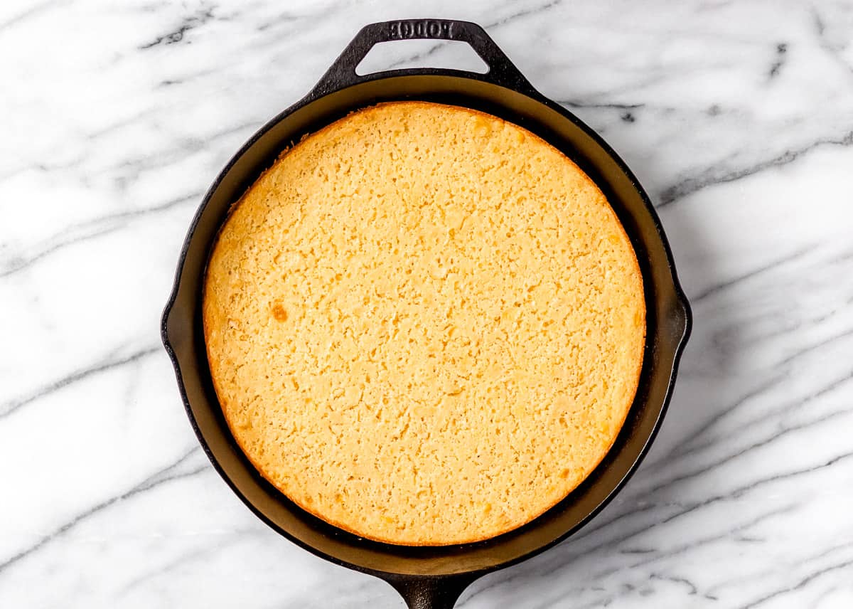 Baked corn soufflpread the batter evenly into the prepared casserole dish. casserole in a cast iron skillet on a marble background