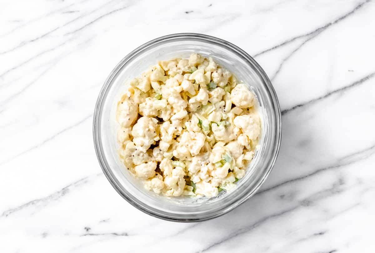 Cauliflower salad in a glass bowl over a marble background