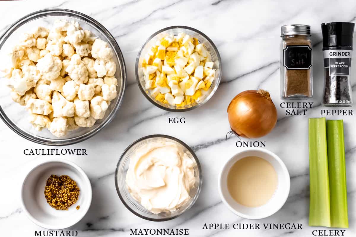 Ingredients to make keto potato salad on a marble background with labels