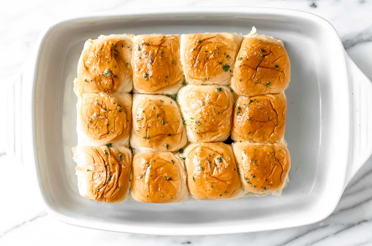 Sliders in a baking dish topped with garlic butter sauce