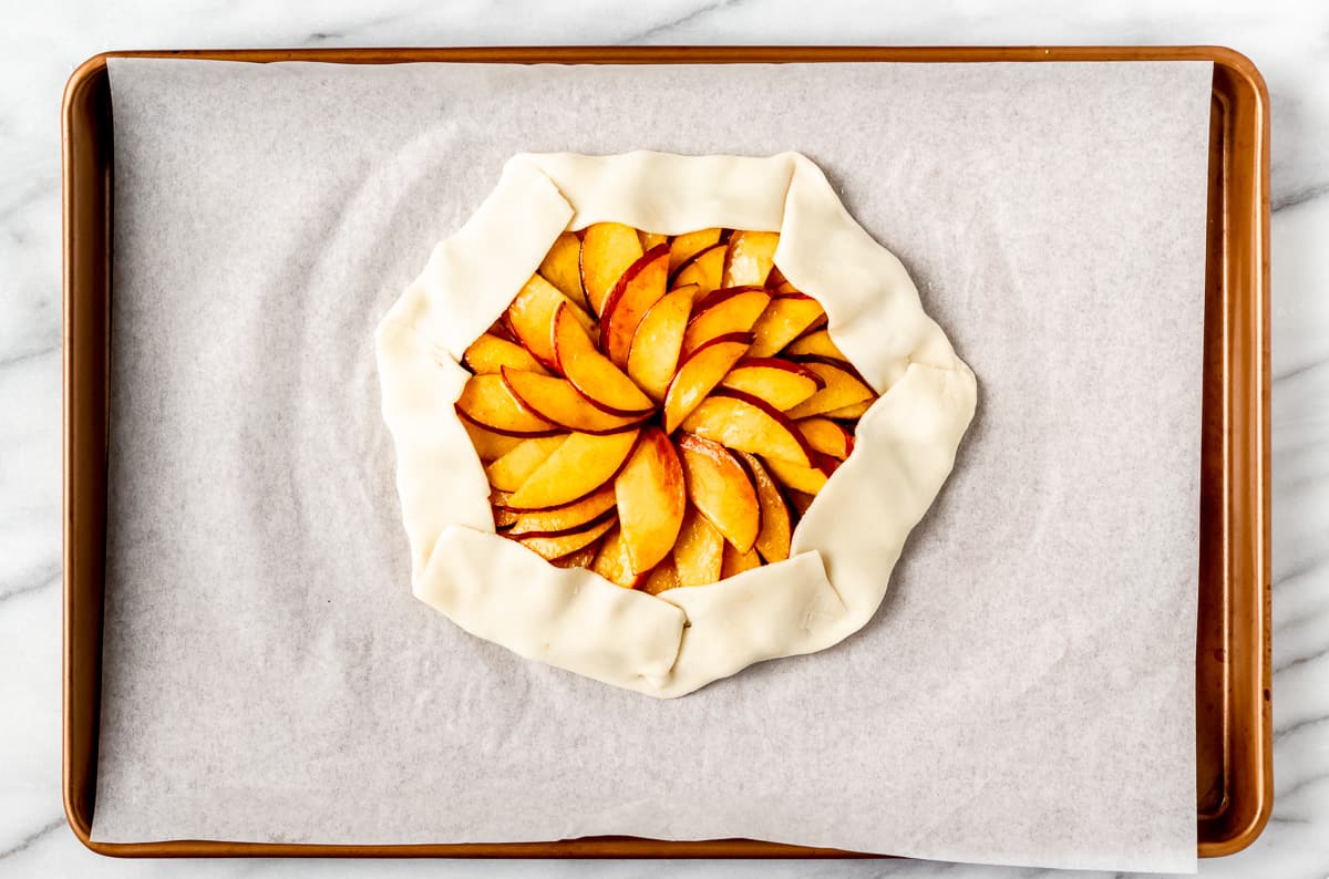 Overhead view of a unbaked peach galette on parchment paper