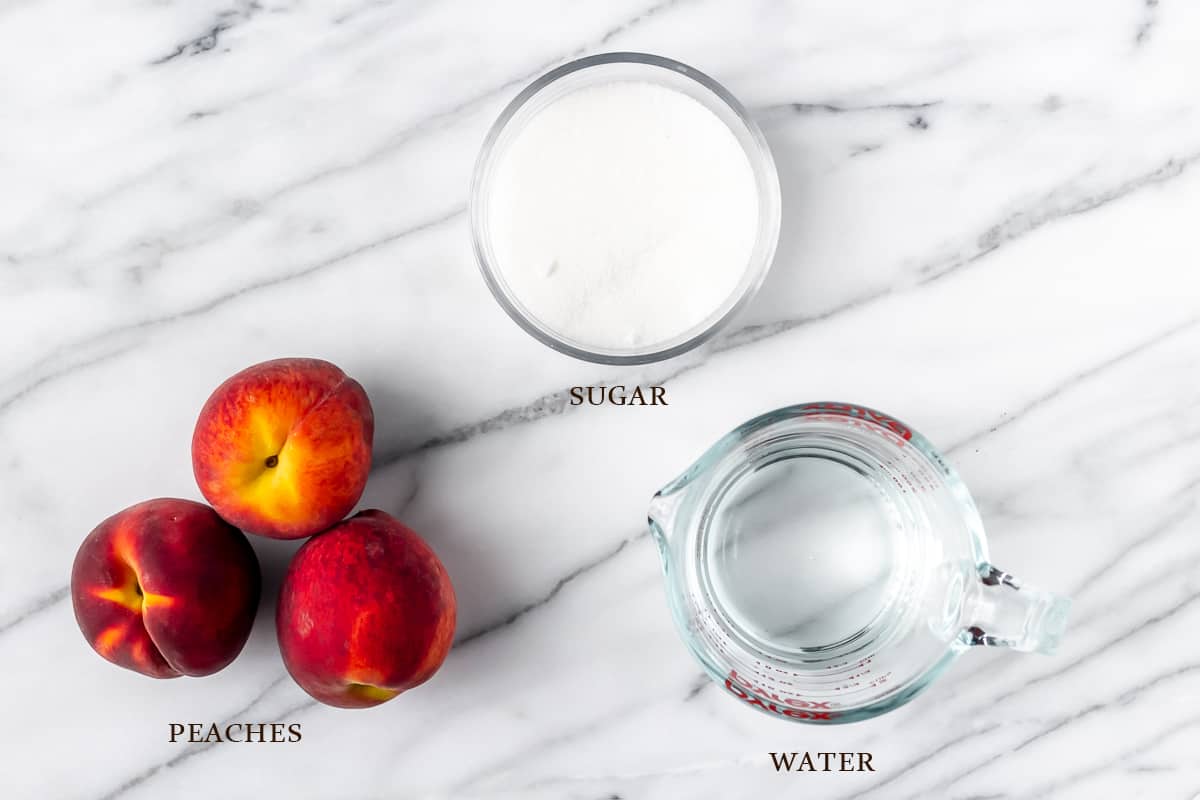 Ingredients to make peach syrup on a marble background with labels
