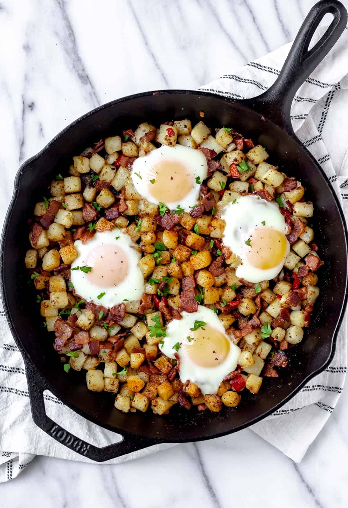 Potato hash with bacon and eggs in a cast iron skillet