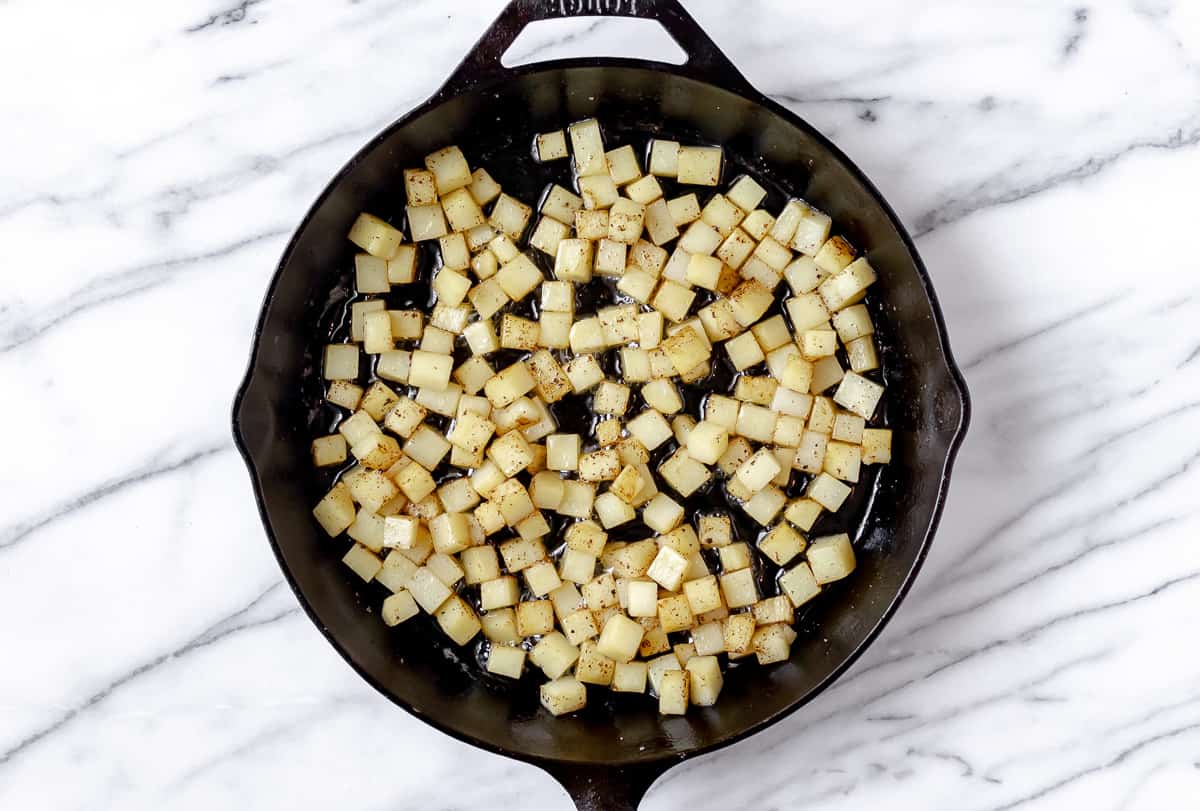 Diced potatoes cooking in a cast iron skillet