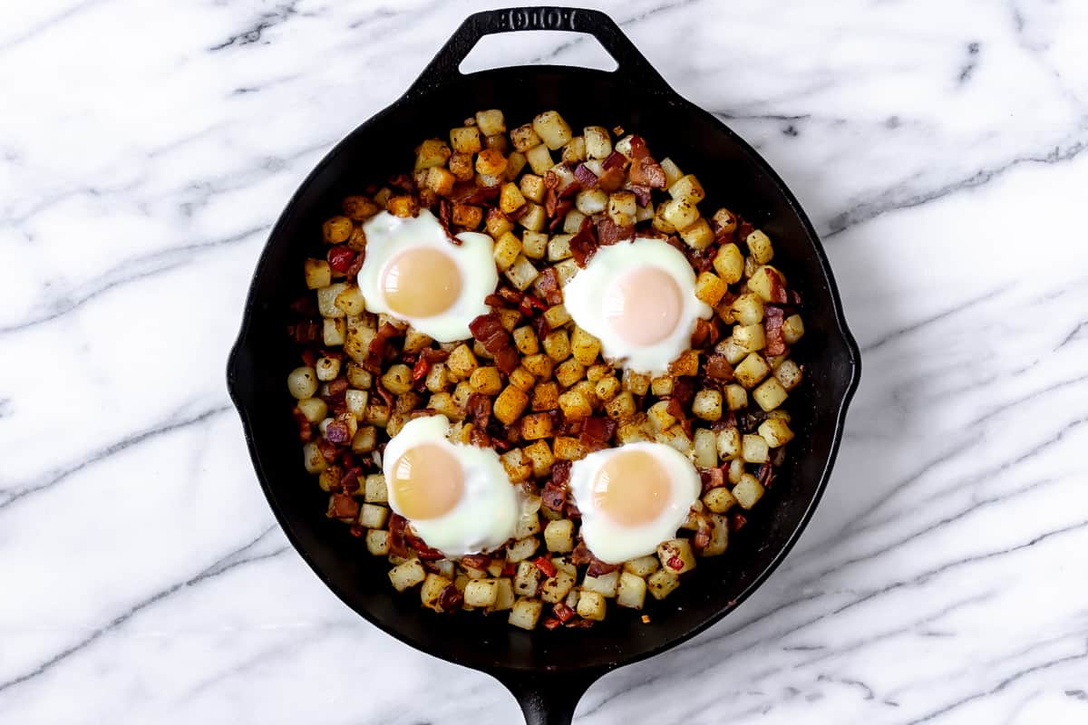 Breakfast hash with potatoes, bell pepper, onion, bacon and eggs in it