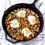 Potato hash with bacon and eggs in a cast iron skillet