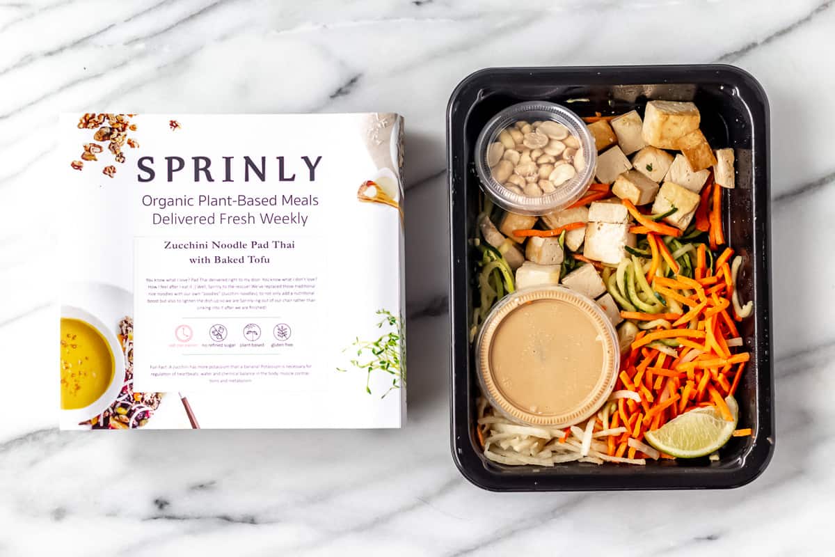 Sprinly Zucchini Noodle Pad Thai with Baked Tofu in package on a marble background