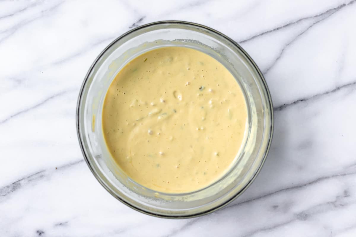 Amish potato salad dressing in a glass bowl on a marble background