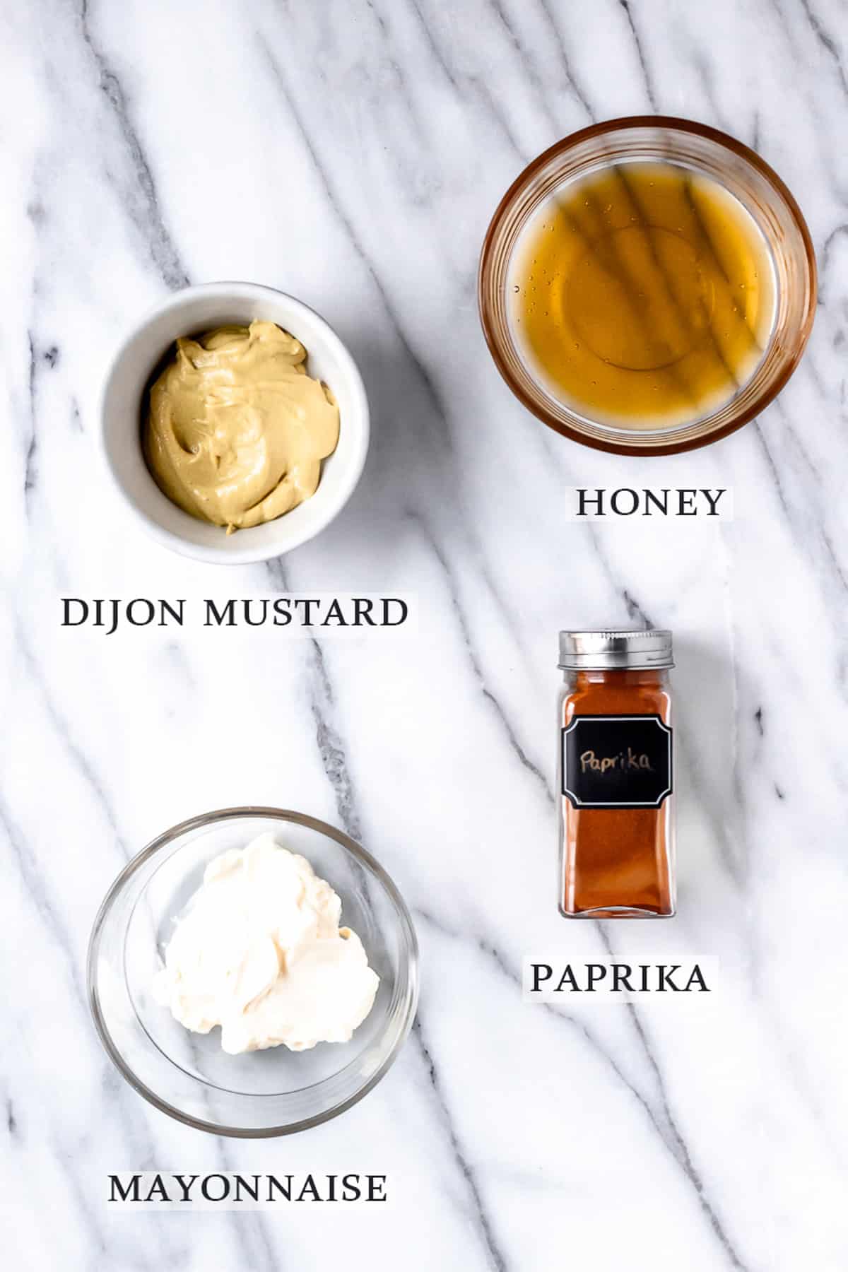 Ingredients needed to make honey mustard dipping sauce on a marble backdrop with text overlay