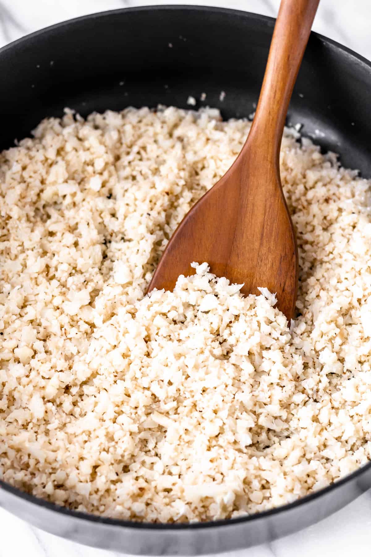 Close up of garlic cauliflower rice being pushed up with a wood turner