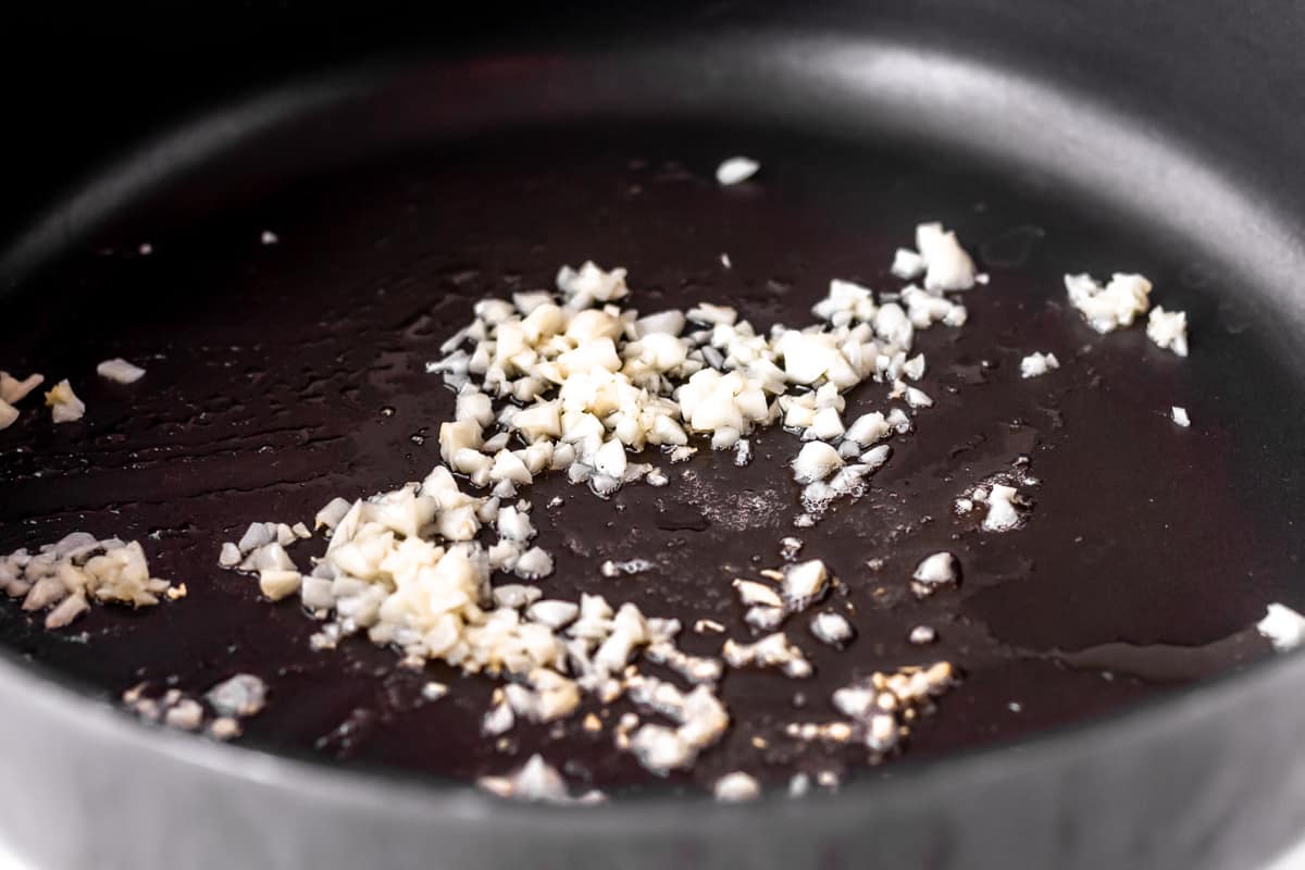 Garlic cooking in butter in a black skillet